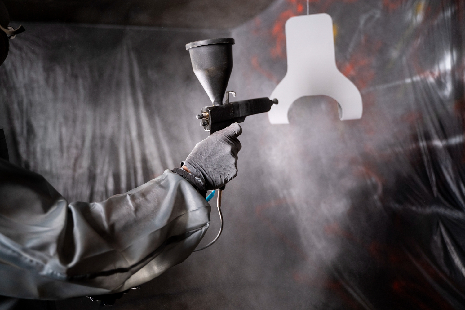 A close-up of a person applying a conductive paint to a 3D printed model with a small brush.