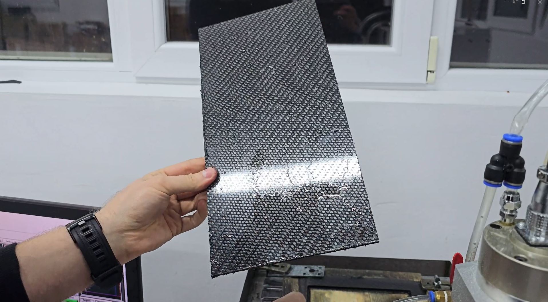 A close-up, detailed photo of a finished, cured 3D printed part with a sleek carbon fiber-infused finish.