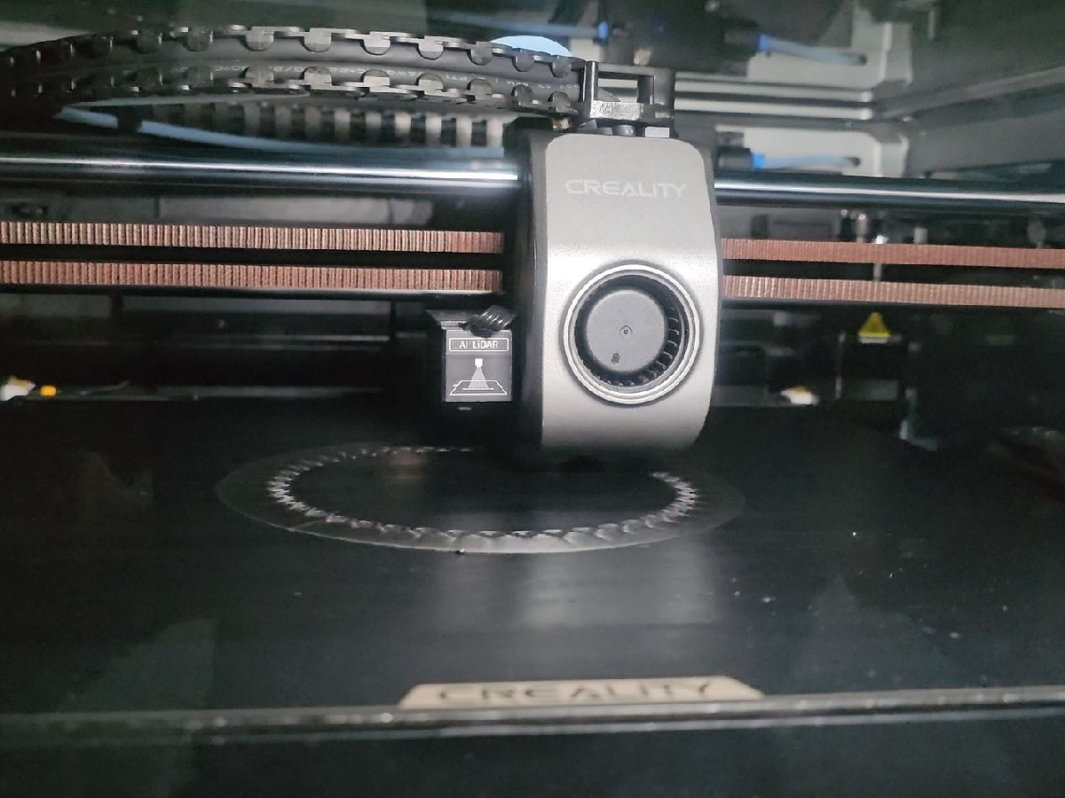 A detailed closeup of the extruder and print bed of a modern FDM 3D printer in operation.