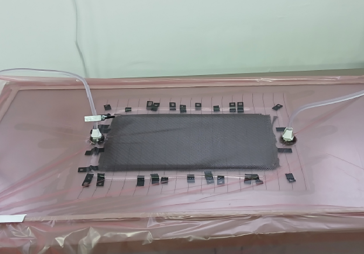 A top-down shot of a person applying a dark liquid carbon resin into the porous surface of a 3D printed model.